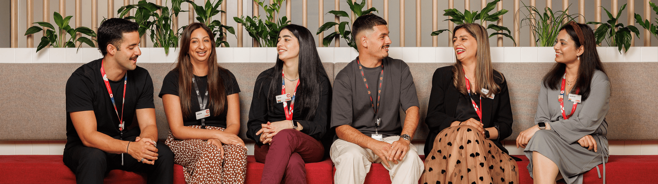 A variety of Corporate team members sitting together on a long couch.