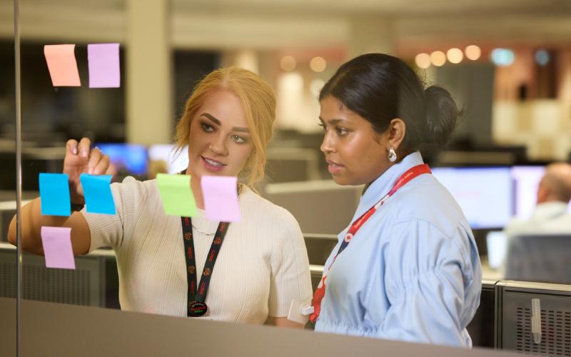 Two female graduates working together at the Coles Store Support Centre