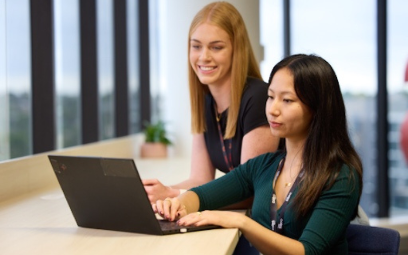 Two Female Coles graduates working together while sitting at a bench
