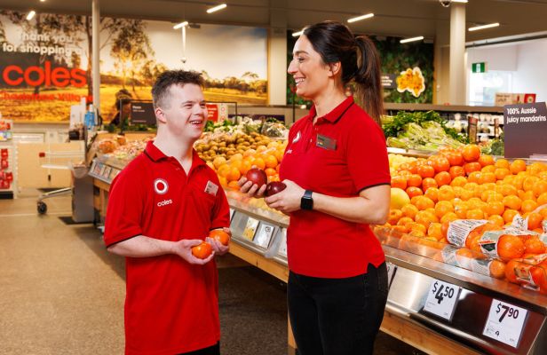 Two Coles team members in a supermarket. One of them has a disability.