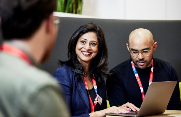 Three Coles team members sitting at a table with a laptop