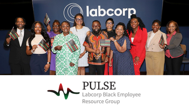 A group of individuals stand together in front of a wall displaying the Labcorp logo during a Juneteenth celebration hosted by the PULSE ERG.