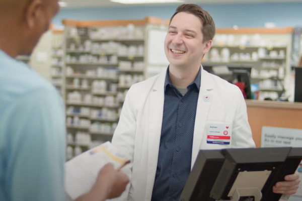 Male pharmacist smiling at the pharmacy counter