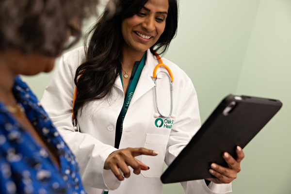 Oak Street Health provider smiling while sharing information on a tablet with a patient.