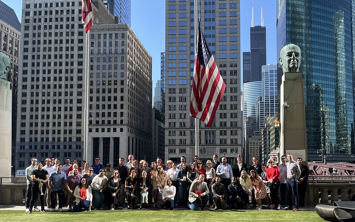 Group photo taken outside of the Chicago office in front of a flag raising.