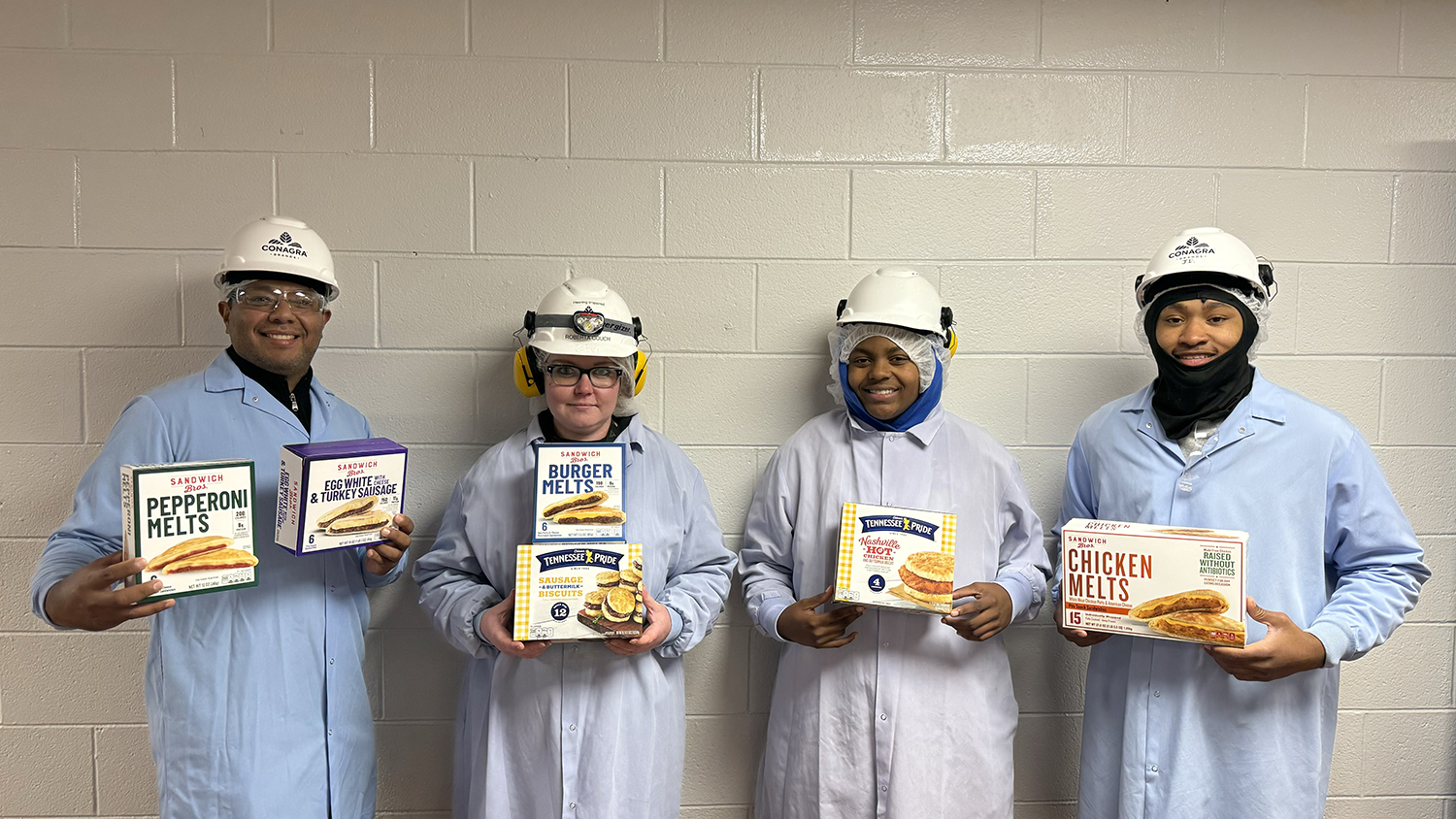 Four employees holding boxes of Sandwich Bros.