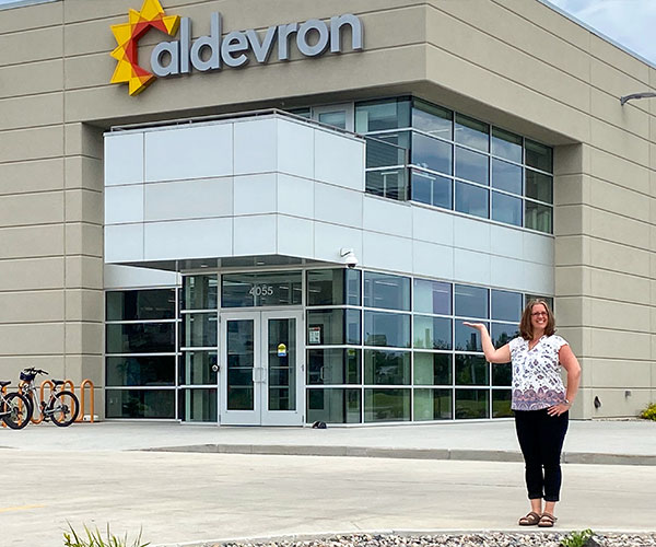 woman standing in front of an office building with aldevron sign