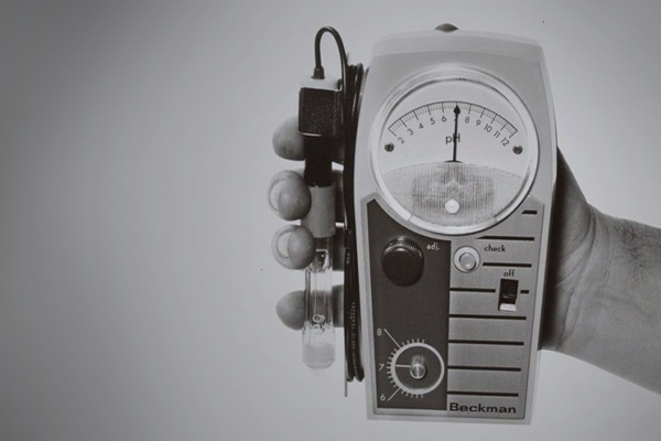 a hand holding Beckman's first electronic pH meter