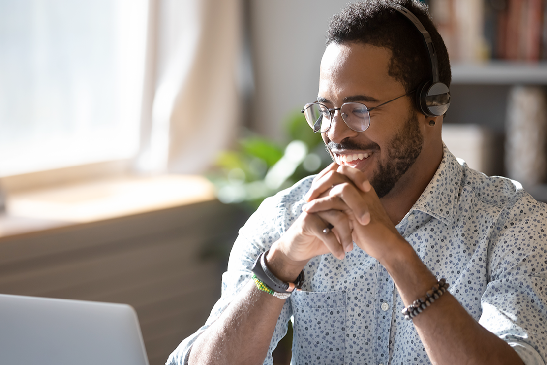 man sitting at desk in front of a laptop wearing a headset