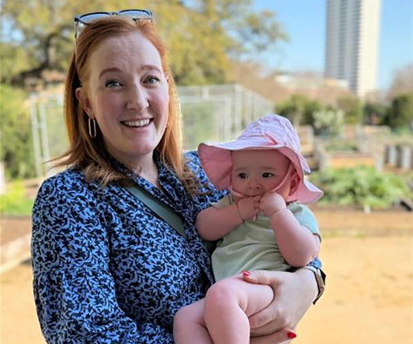 image of sydnee eldridge, standing holding a baby