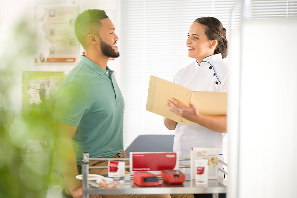 two people have a conversation in an office, with a tray of HemoCue products in front of them