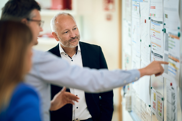 a group of people look at charts on a bulletin board