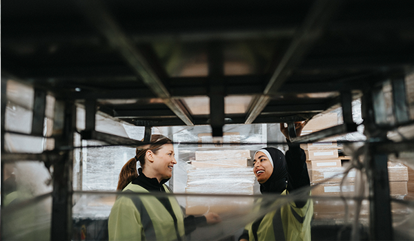 two women have a conversation in a warehouse