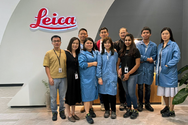 group of associates standing in an office building lobby in front of a Leica sign