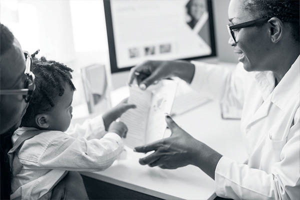 female doctor reviews a pamphlet with a father and his young son