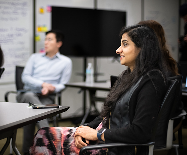 image of asha sitting in a conference room with others