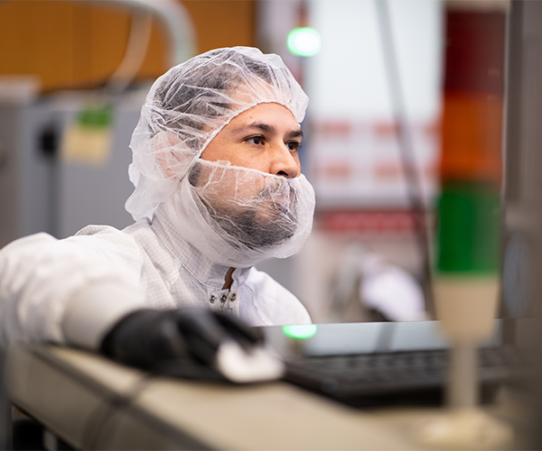 man in hair and face net using a computer