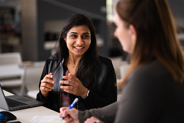 woman sitting in front of a laptop speaking to another woman