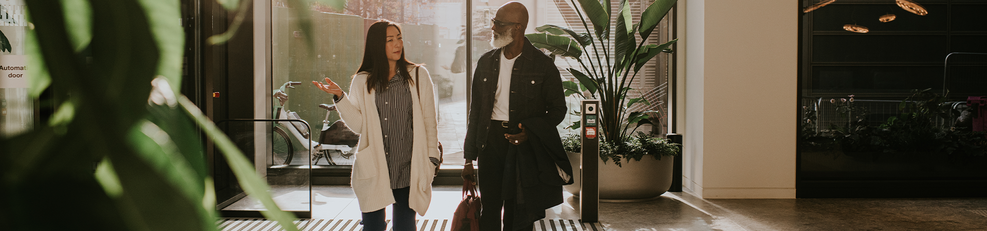 a man and a woman walk through the front doors of a building having a conversation