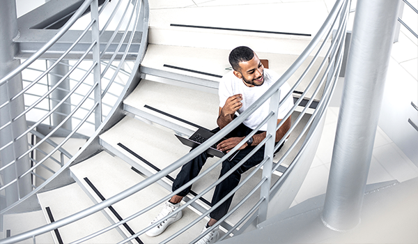man on a computer sits on a spiral staircase