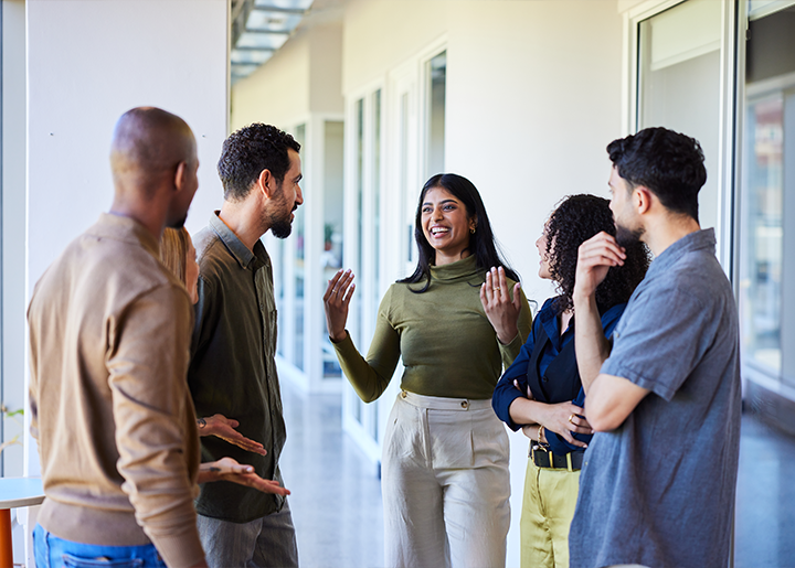 a group of people stand in a well lit hallway having a discussion