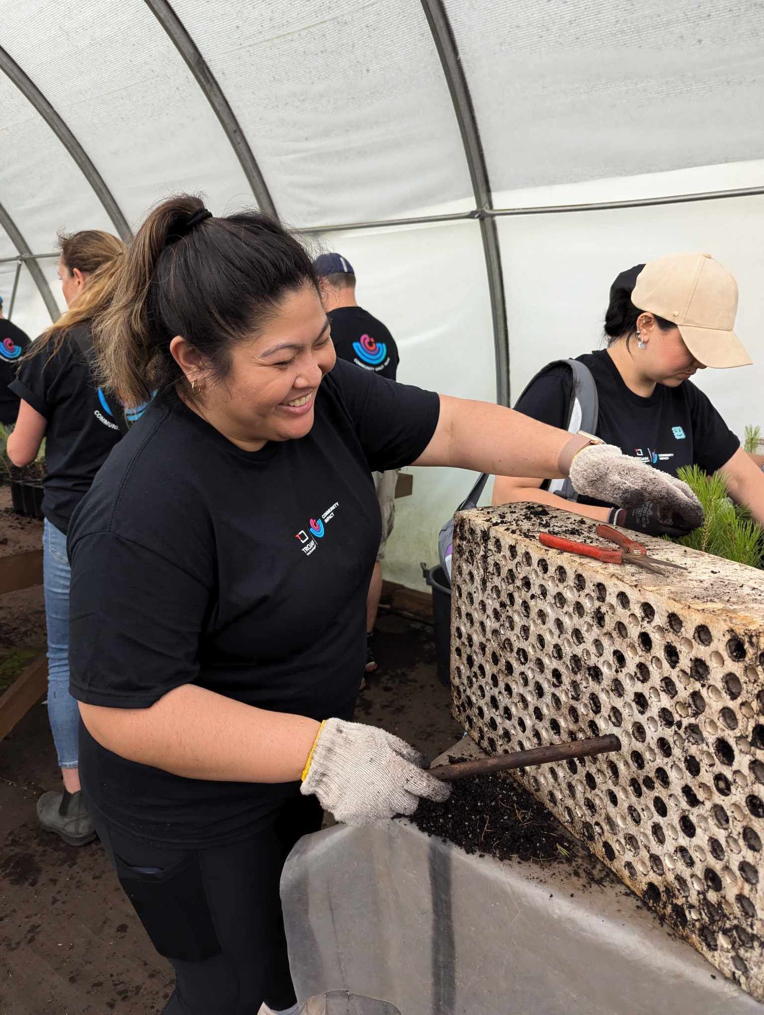 A Trojan Technologies employee smiles as she removes tree saplings for planting at a company volunteer event