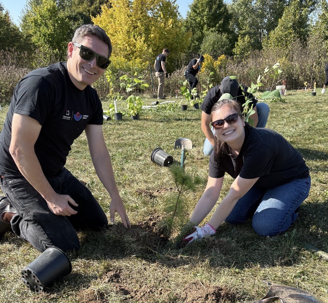 Trojan Technologies employees smile as they plant a tree at a volunteer event