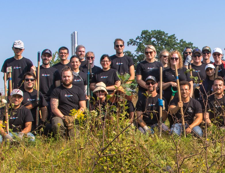 A large group of Trojan Technologies employees smile in a field at a volunteer event.