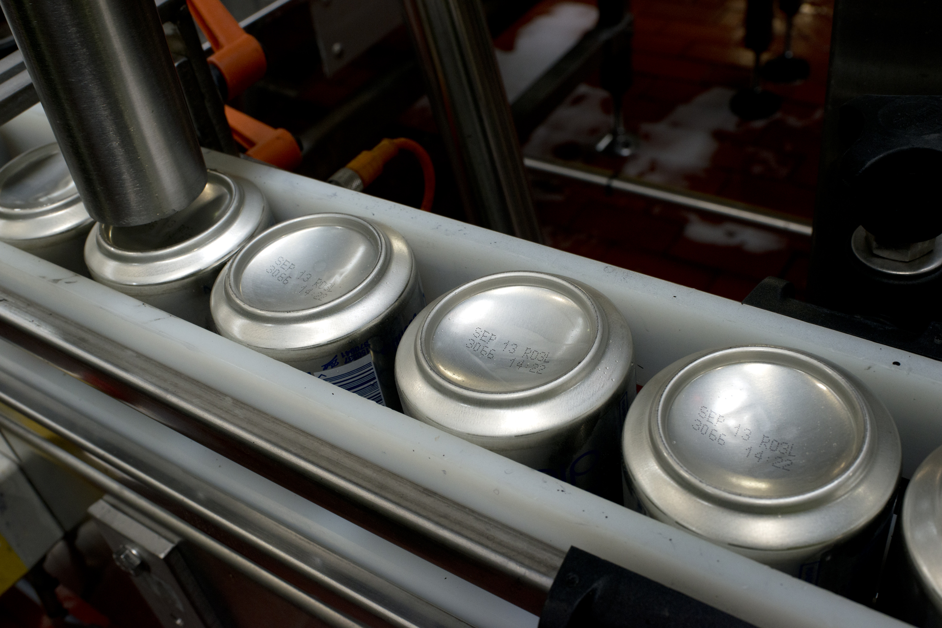 Cans on an assembly line being printed with "sell by" dates