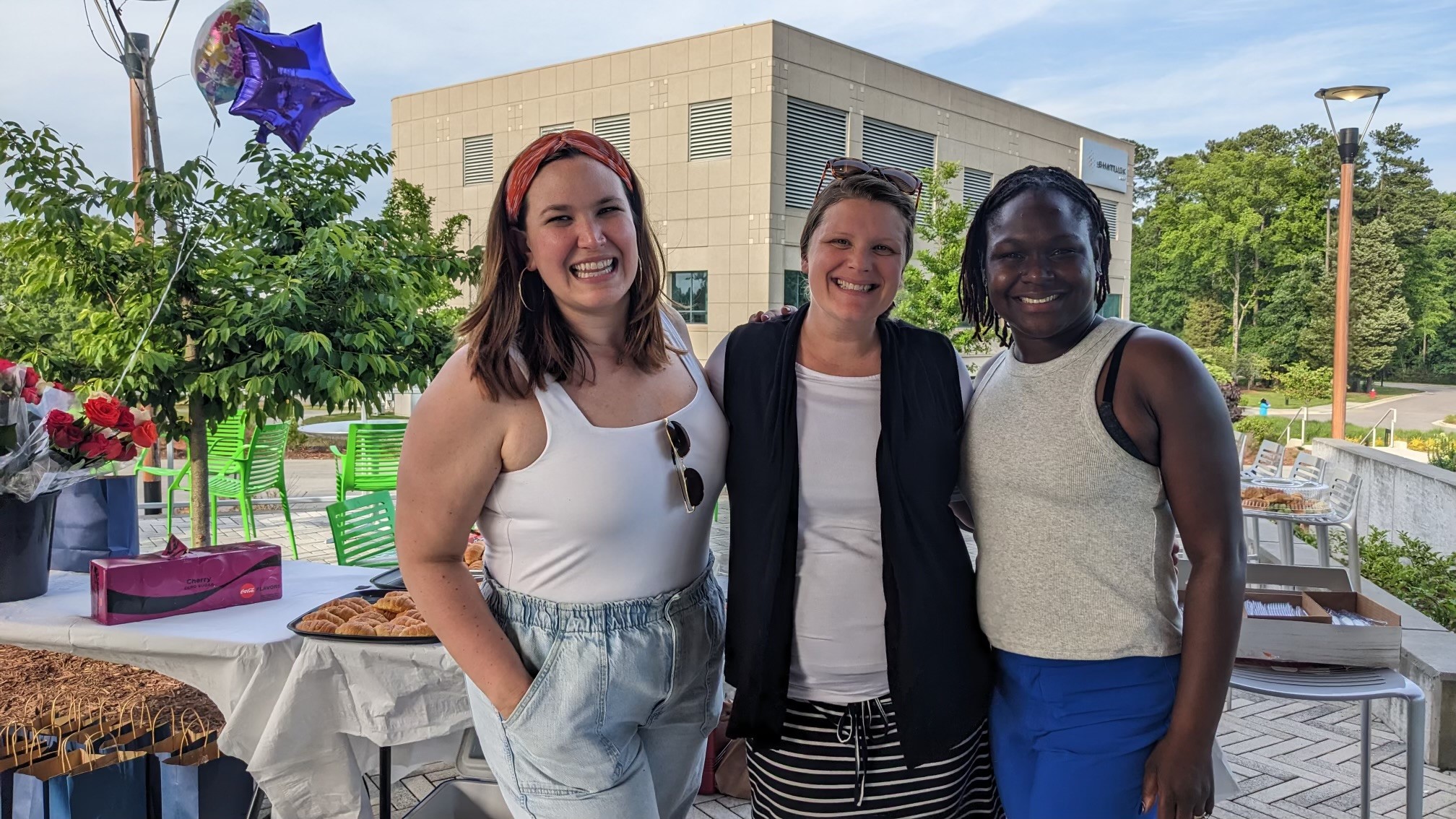 Three team members smile together at an event.