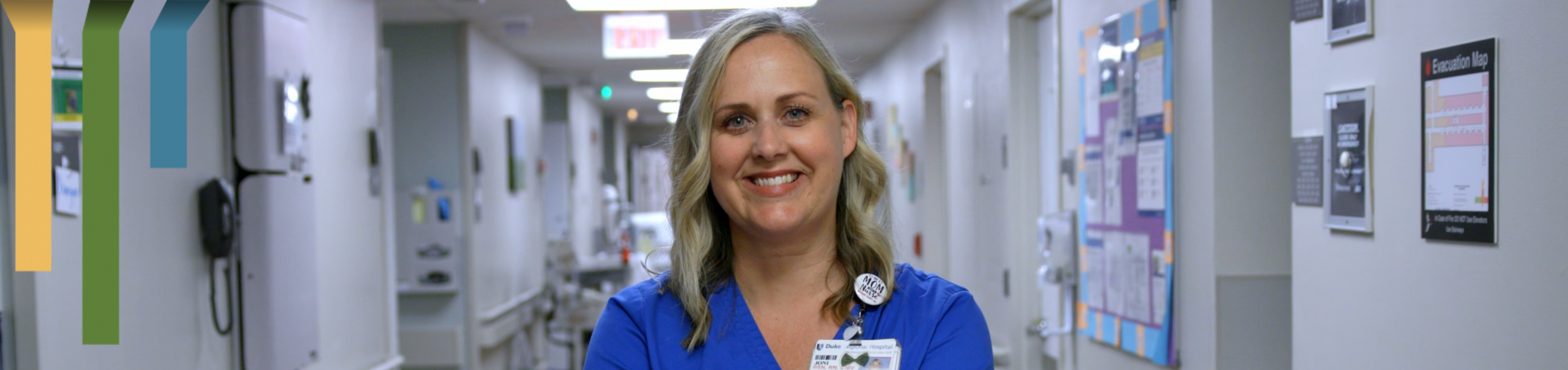 female team member smiles in scrubs.