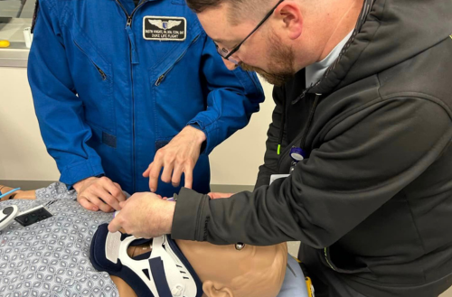 Two individuals work together on a mannequin.