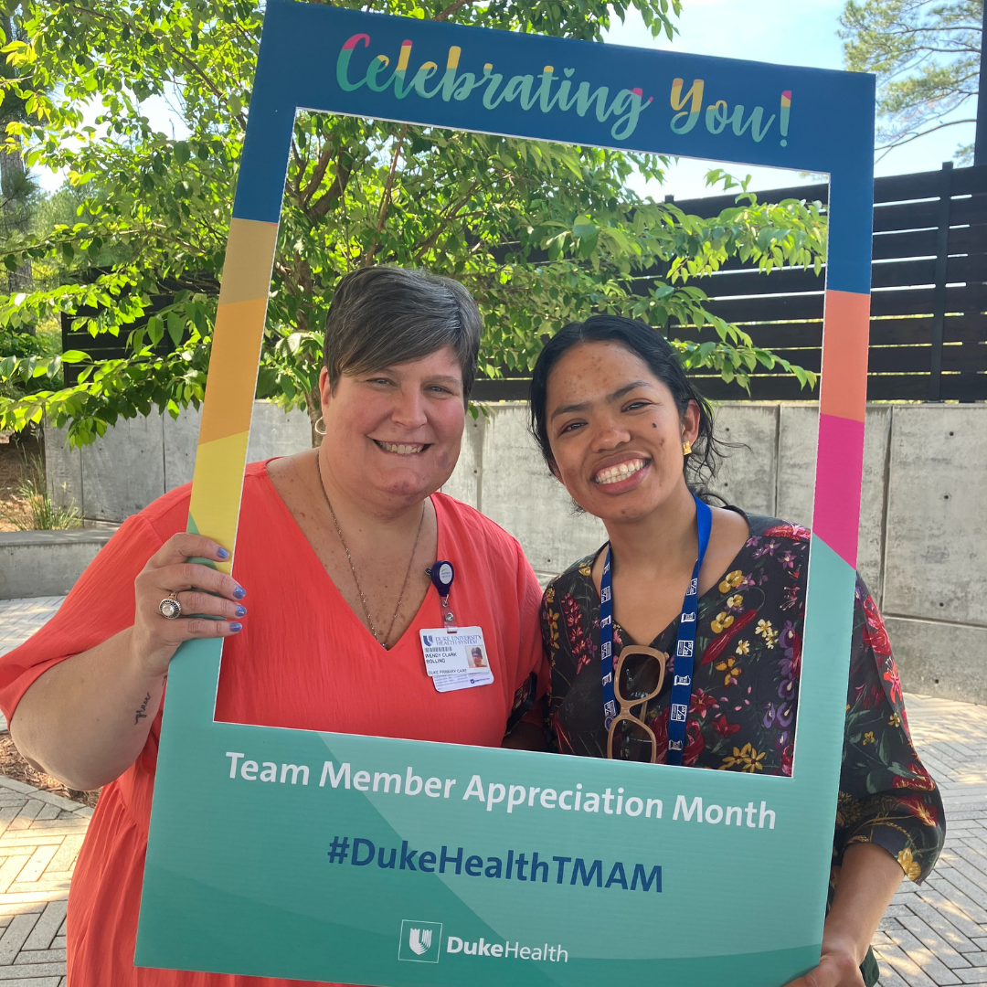 Team members smile with photo props during appreciation event. 