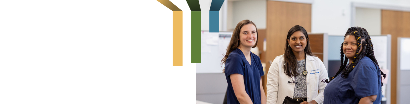 Three female team members smile in a clinic.