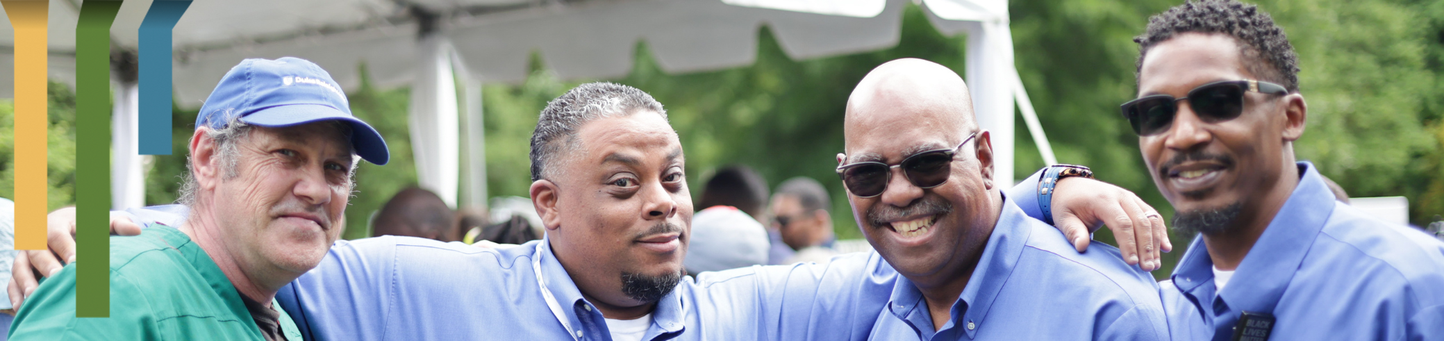 Four Duke Raleigh Campus team members smile together at a social gathering.