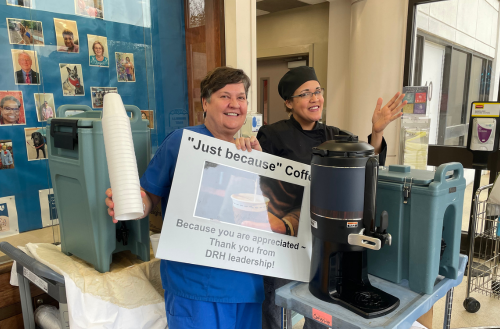 Team members smile with just because signs and food. 