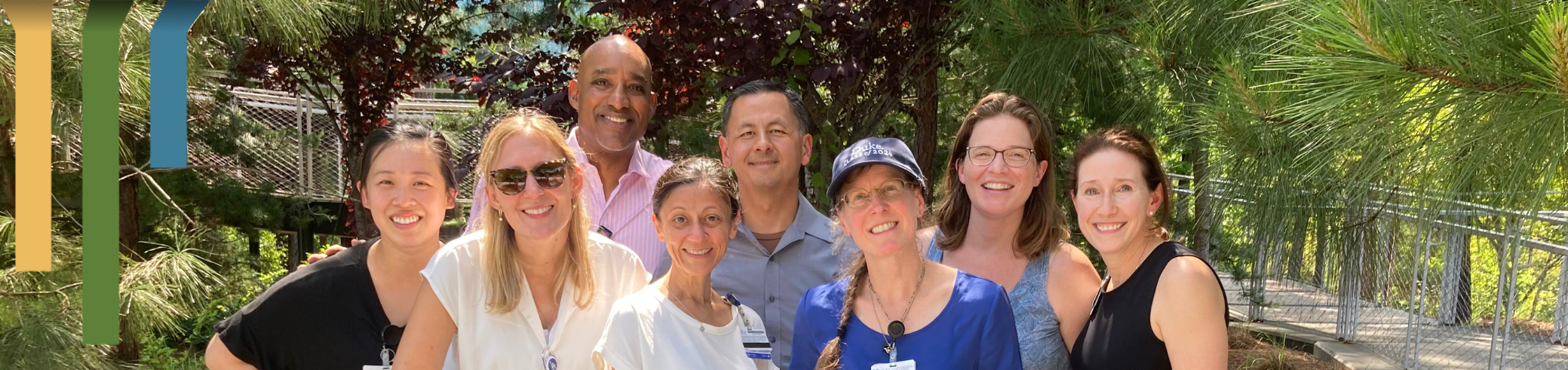 Team members smile together on campus grounds.