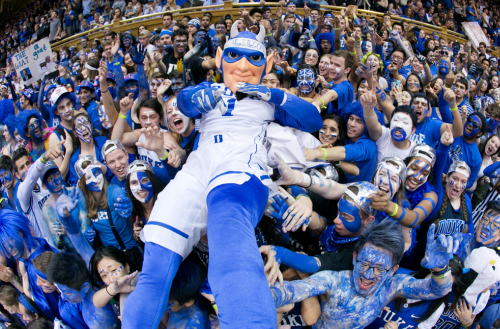 Duke Blue Devil in a crowd painted blue at a Cameron Indoor Stadium basketball game.