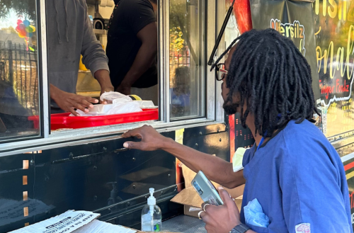 Male team member in scrubs gets lunch from a food truck.