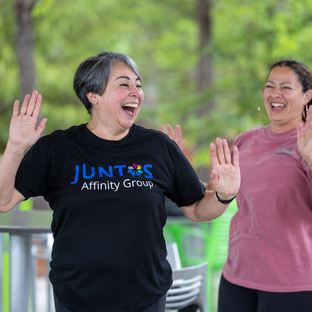 Two female team members smile together working out during an affinity group gathering.