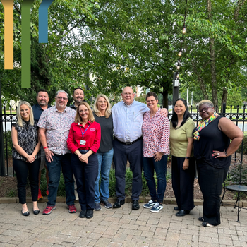 A group of male and female IT team members smiles together outside.