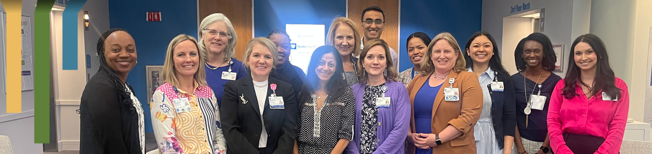 Team members smile in a group with colorful tops.