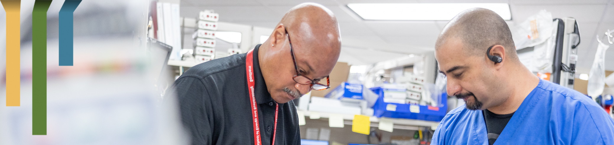 Two male IT professionals work on equipment together at Duke Health.
