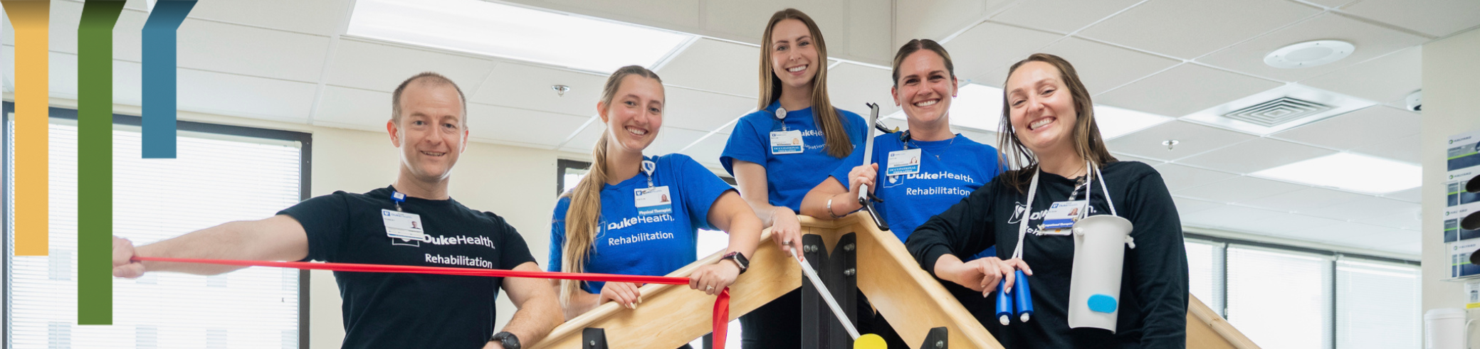 Five rehab team members smile with equipment.