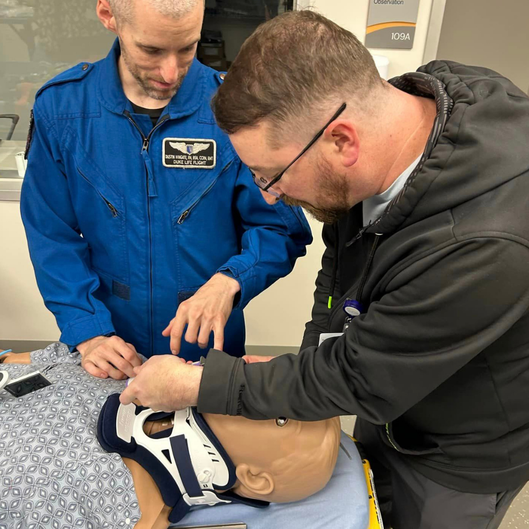 Two male team members work together on a training device.