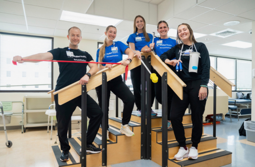 Five rehab team members pose together with equipment.