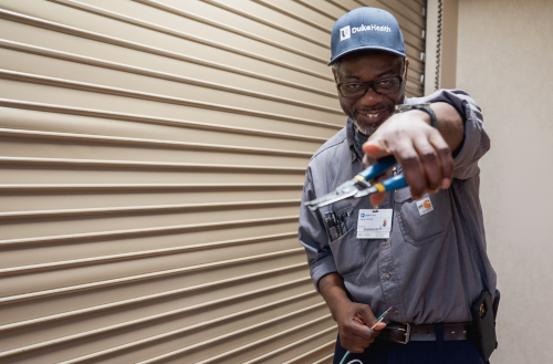 Male team member smiles while fixing electrical.