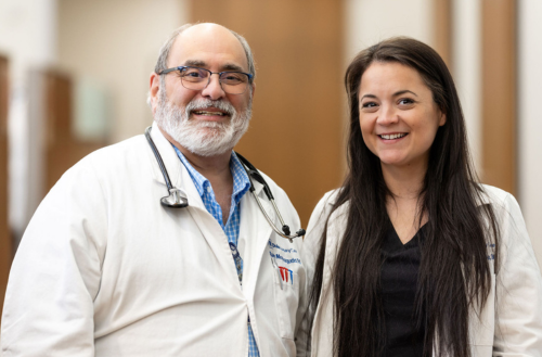 Two providers smile in white coats together.