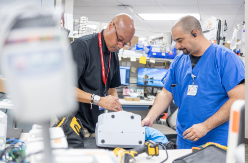 Two male team members work on equipment together.