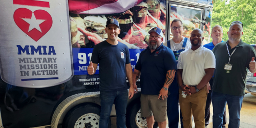 Military and veteran team members smile together at a volunteer event.